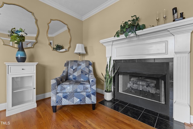 sitting room featuring crown molding, baseboards, a tiled fireplace, and wood finished floors