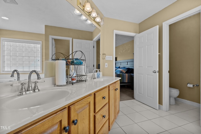 bathroom featuring double vanity, toilet, a sink, and tile patterned flooring