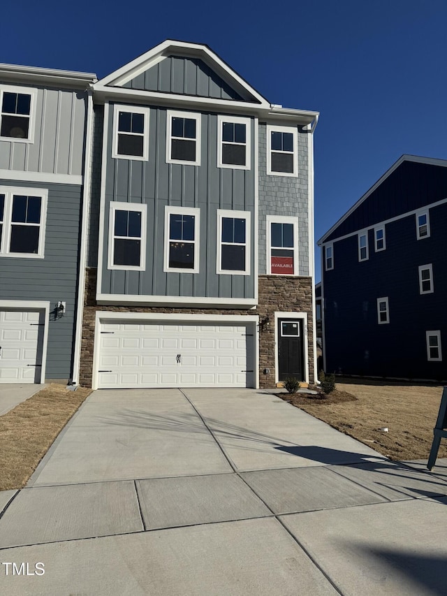 view of front of house featuring board and batten siding, an attached garage, concrete driveway, and stone siding