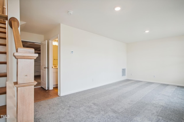 carpeted empty room featuring recessed lighting, baseboards, visible vents, and stairway
