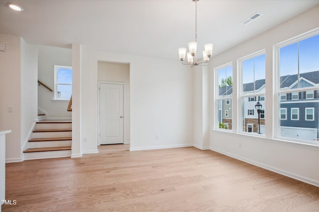 unfurnished dining area featuring visible vents, stairway, baseboards, light wood finished floors, and a chandelier