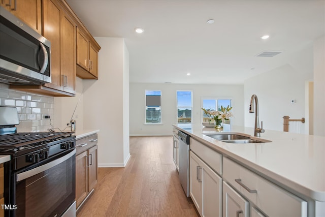 kitchen featuring visible vents, light countertops, a sink, backsplash, and stainless steel appliances