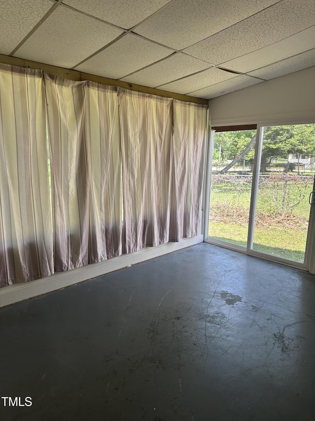 empty room featuring concrete floors and a drop ceiling