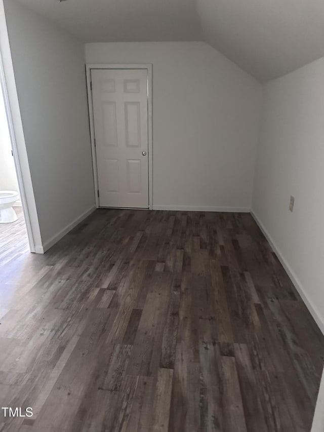 additional living space featuring baseboards, dark wood finished floors, and vaulted ceiling