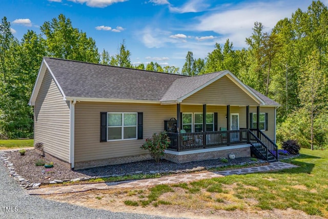 ranch-style home with covered porch, roof with shingles, and a front yard
