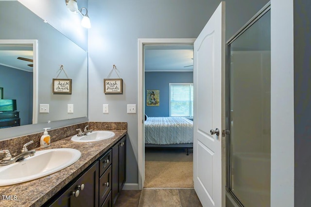 ensuite bathroom featuring a stall shower, ornamental molding, double vanity, and baseboards