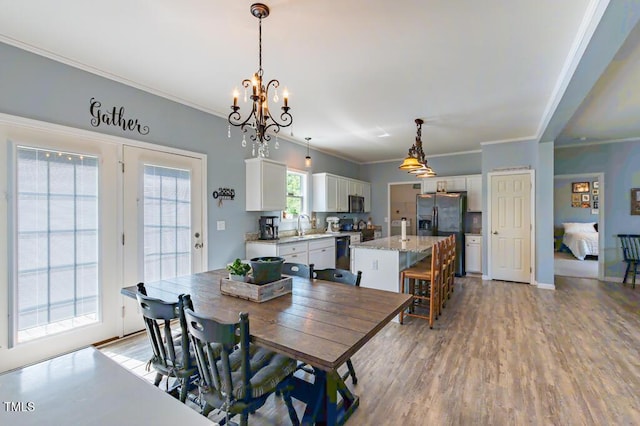 dining area featuring light wood-style floors, crown molding, a chandelier, and baseboards