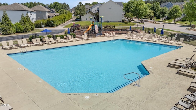 community pool with fence, a residential view, and a patio area