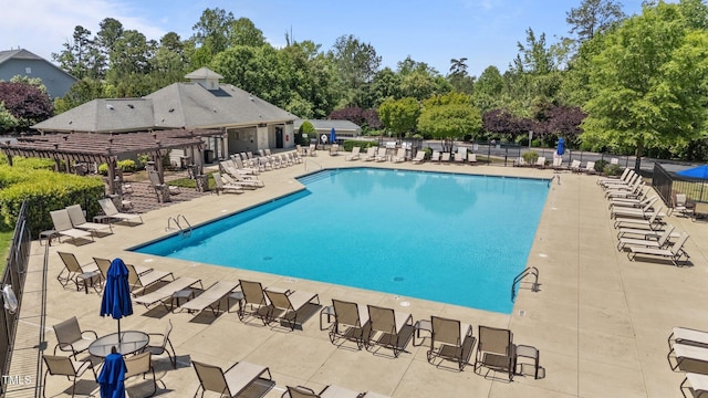 community pool featuring view of scattered trees, a patio area, and fence