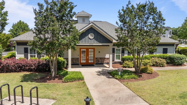 view of front facade with french doors, a front lawn, and a shingled roof