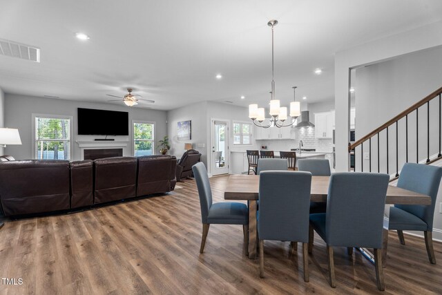 dining space with a ceiling fan, wood finished floors, recessed lighting, a chandelier, and stairway