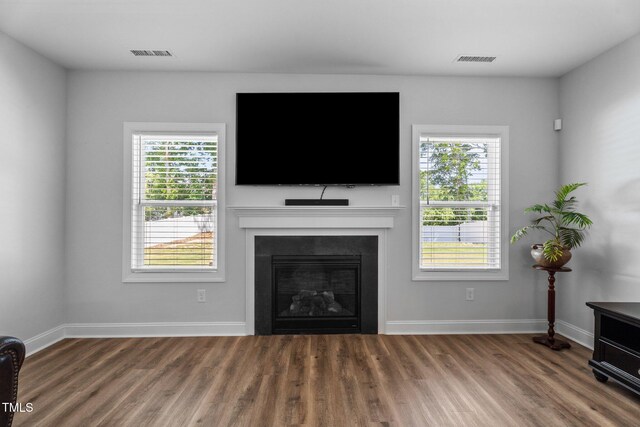 living area featuring wood finished floors, plenty of natural light, baseboards, and a glass covered fireplace