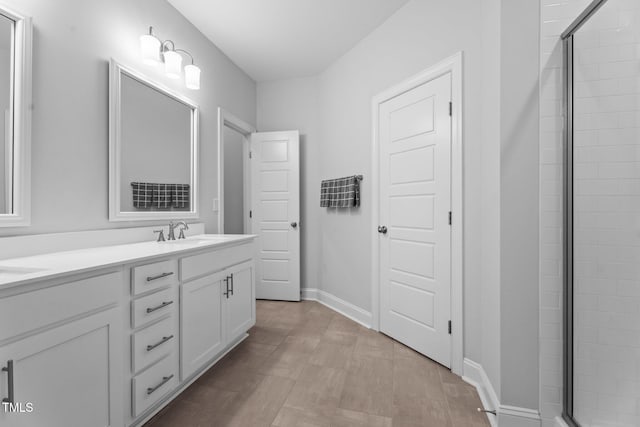 bathroom featuring a stall shower, double vanity, and baseboards