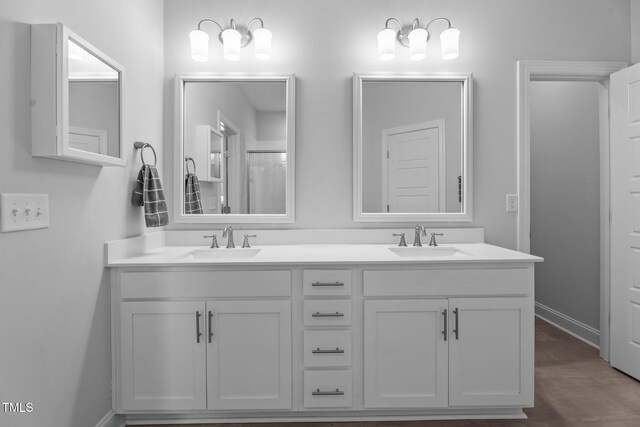 bathroom with double vanity, baseboards, and wood finished floors