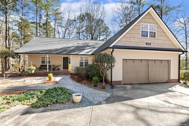 view of front facade featuring a garage, roof with shingles, covered porch, and concrete driveway
