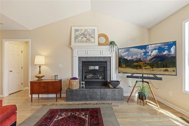 living area with baseboards, vaulted ceiling, wood finished floors, and a fireplace