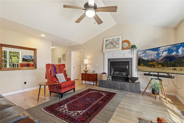 living area with baseboards, ceiling fan, wood finished floors, and lofted ceiling