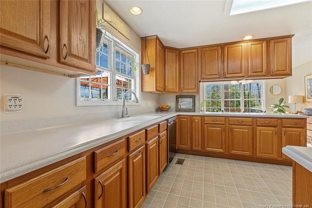 kitchen with brown cabinetry, a sink, and light countertops