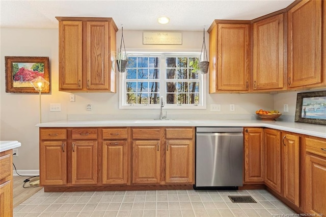 kitchen with stainless steel dishwasher, visible vents, light countertops, brown cabinets, and a sink