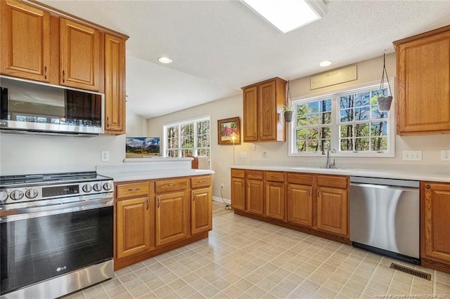 kitchen with stainless steel appliances, brown cabinetry, and a sink