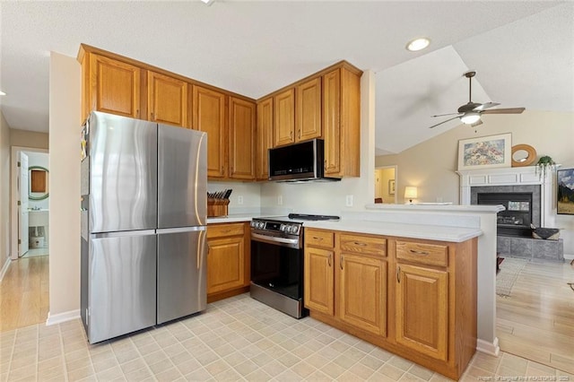 kitchen featuring a ceiling fan, a peninsula, appliances with stainless steel finishes, and light countertops