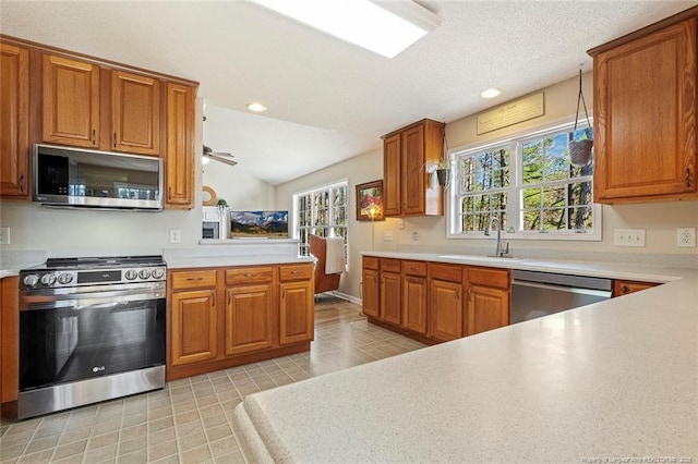 kitchen with a sink, appliances with stainless steel finishes, brown cabinets, and light countertops