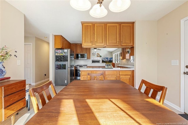 kitchen featuring a peninsula, baseboards, light countertops, a chandelier, and appliances with stainless steel finishes