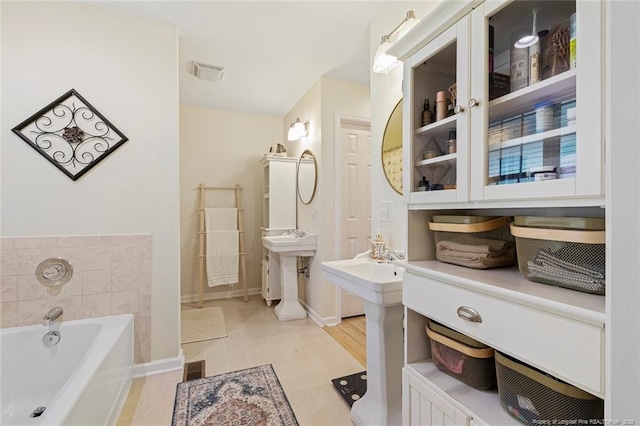 bathroom featuring baseboards, a garden tub, and visible vents