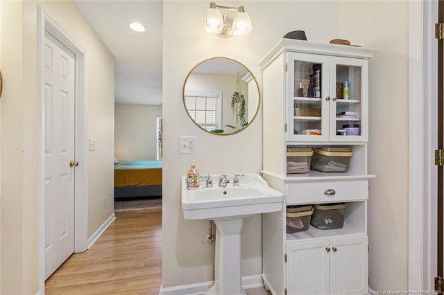 bathroom with baseboards, a sink, wood finished floors, and ensuite bathroom