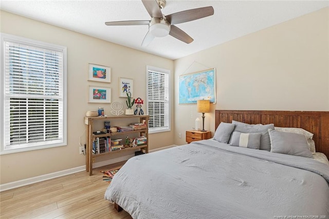 bedroom with light wood-style floors, a ceiling fan, and baseboards