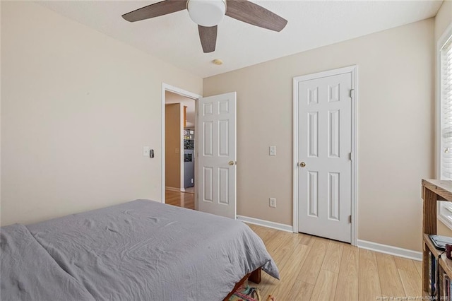 bedroom with light wood-style floors, a ceiling fan, and baseboards