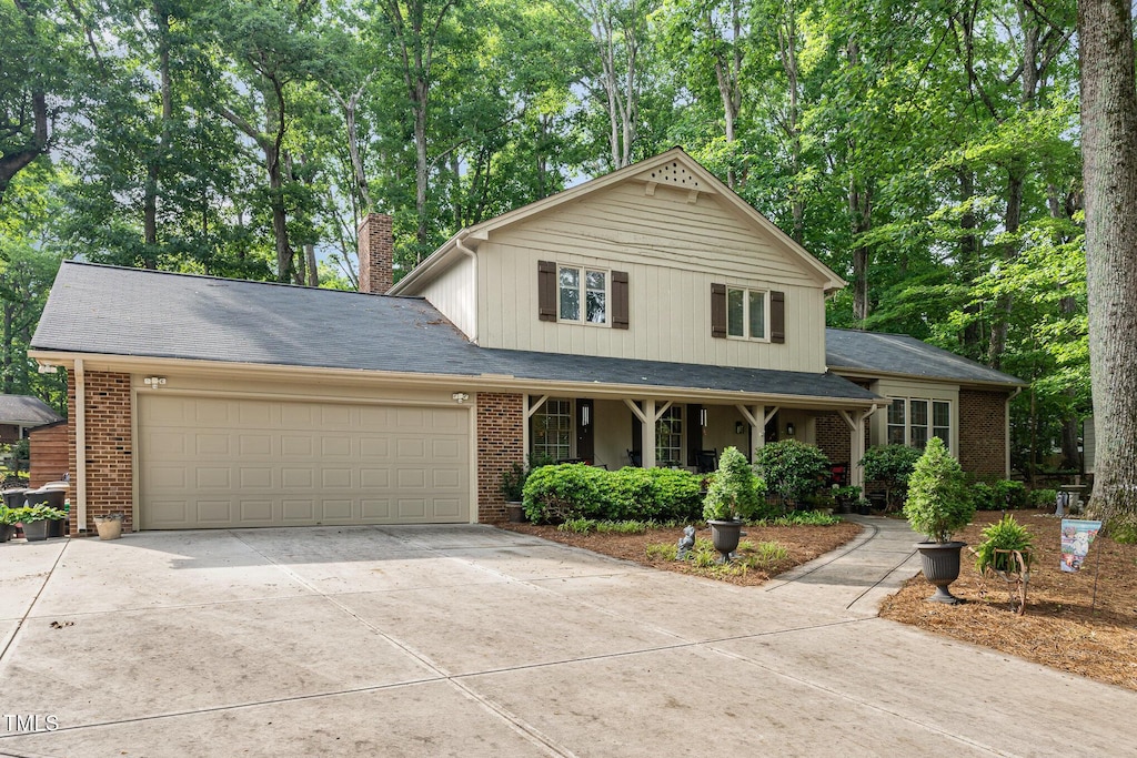 125 Amesbury Ln, Cary, NC 27511 - view of front of property with concrete driveway, an attached garage, a chimney, brick siding, and a porch