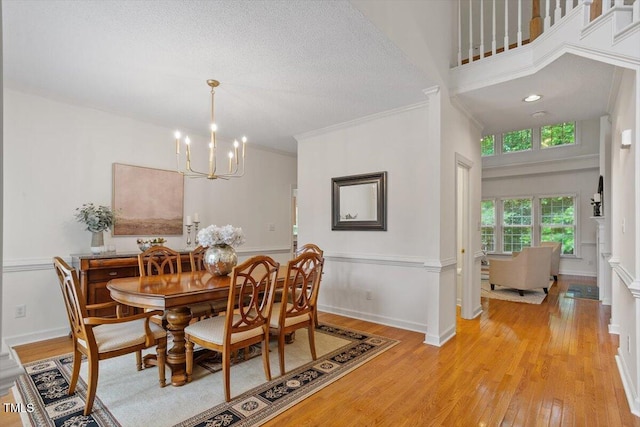 dining area with a chandelier, light wood-style flooring, baseboards, and crown molding