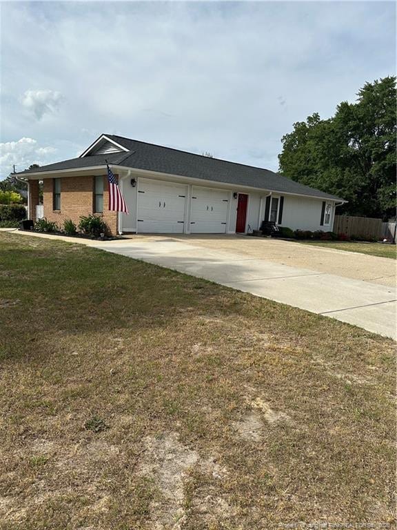 single story home featuring fence, an attached garage, driveway, and a front yard