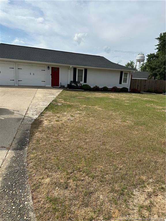 ranch-style house featuring concrete driveway, a garage, a front lawn, and fence