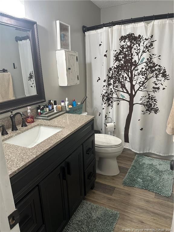bathroom with vanity, a textured ceiling, toilet, and wood finished floors