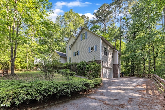 view of side of property with an attached garage, aphalt driveway, and brick siding