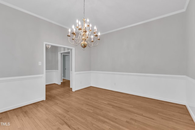 unfurnished dining area featuring baseboards, an inviting chandelier, ornamental molding, and light wood finished floors