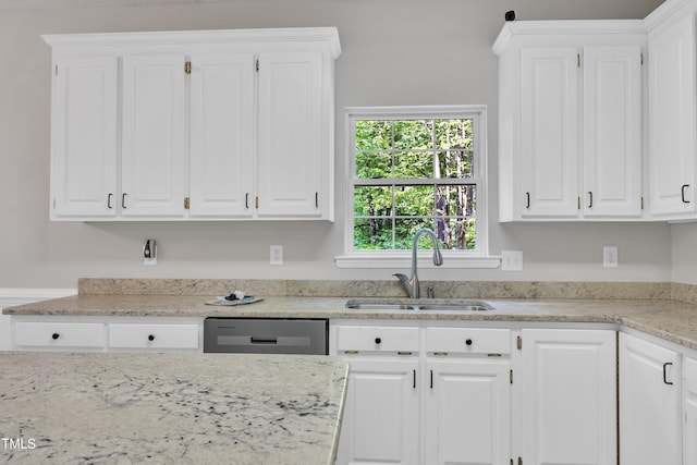 kitchen featuring a sink, light stone counters, white cabinets, and dishwashing machine