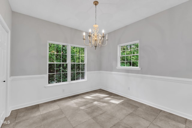spare room featuring baseboards, an inviting chandelier, and visible vents