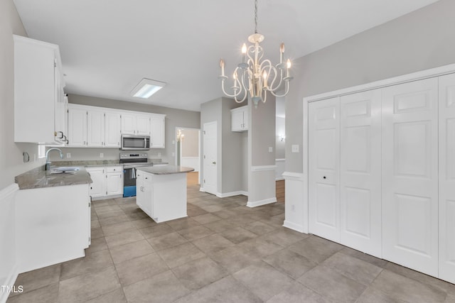 kitchen featuring white cabinets, a sink, a chandelier, a center island, and stainless steel appliances