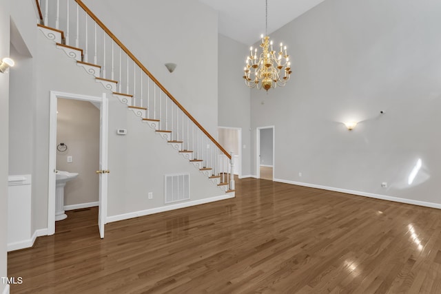 interior space featuring visible vents, an inviting chandelier, stairs, wood finished floors, and a high ceiling