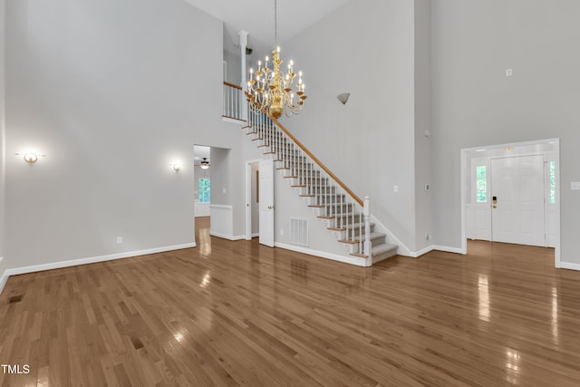 entryway featuring a high ceiling, baseboards, wood finished floors, visible vents, and stairway