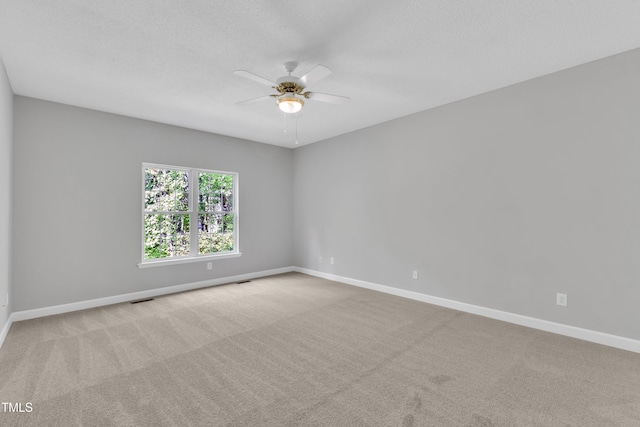 unfurnished room with carpet flooring, ceiling fan, visible vents, and baseboards