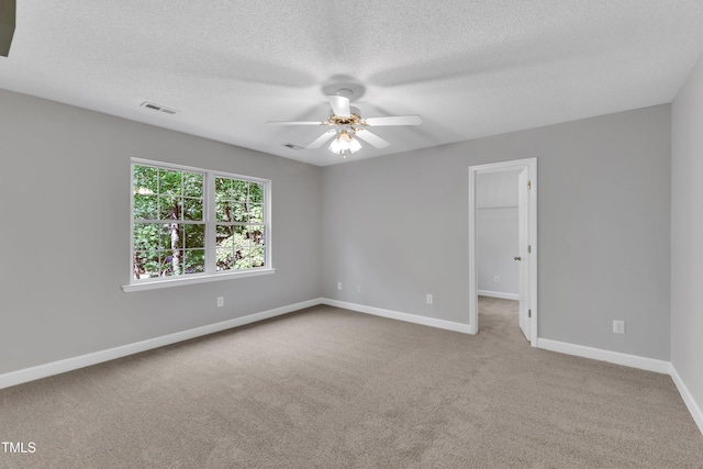 empty room featuring carpet floors, a ceiling fan, baseboards, and visible vents