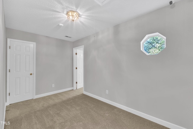 unfurnished bedroom with baseboards, carpet flooring, a textured ceiling, and visible vents