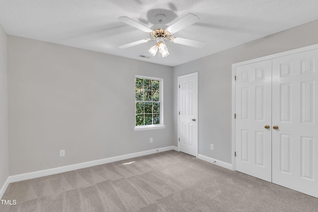 unfurnished bedroom with a ceiling fan, a textured ceiling, visible vents, baseboards, and carpet flooring