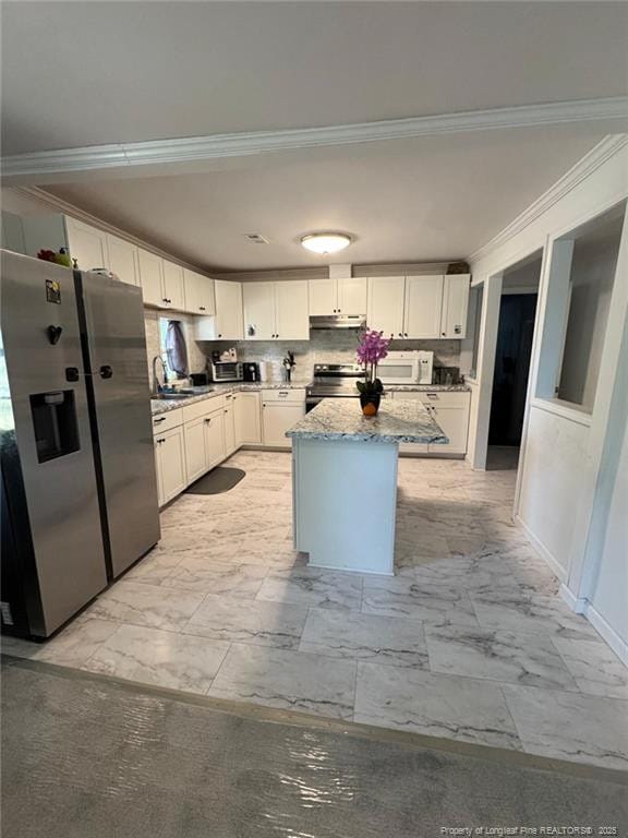 kitchen featuring crown molding, white cabinets, appliances with stainless steel finishes, marble finish floor, and under cabinet range hood