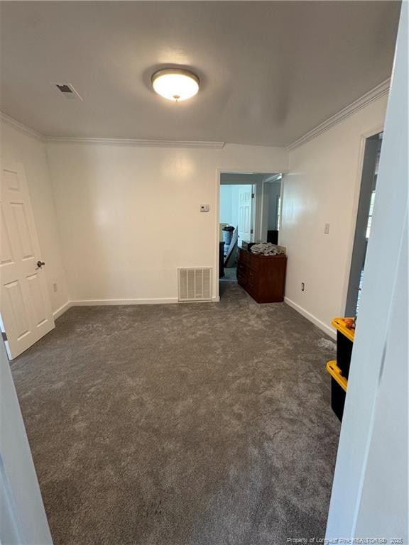 spare room featuring crown molding, baseboards, visible vents, and dark colored carpet