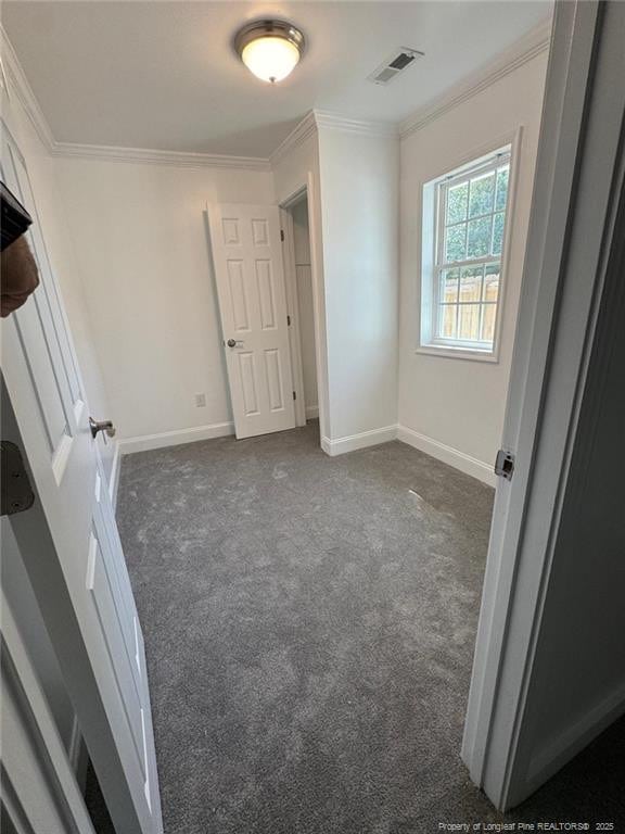 unfurnished bedroom with crown molding, baseboards, carpet, and visible vents
